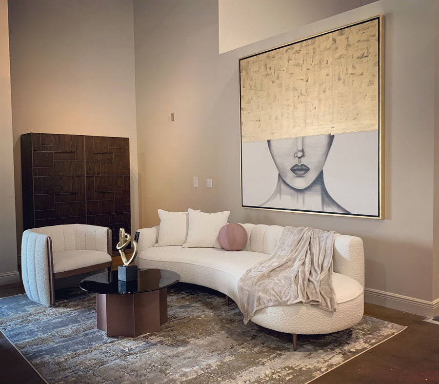 Modern living room with a curved white sofa, round coffee table, and abstract art on the wall.