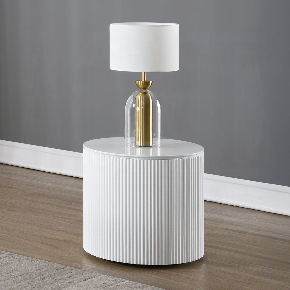 White side table with a gold and glass lamp against a gray wall.