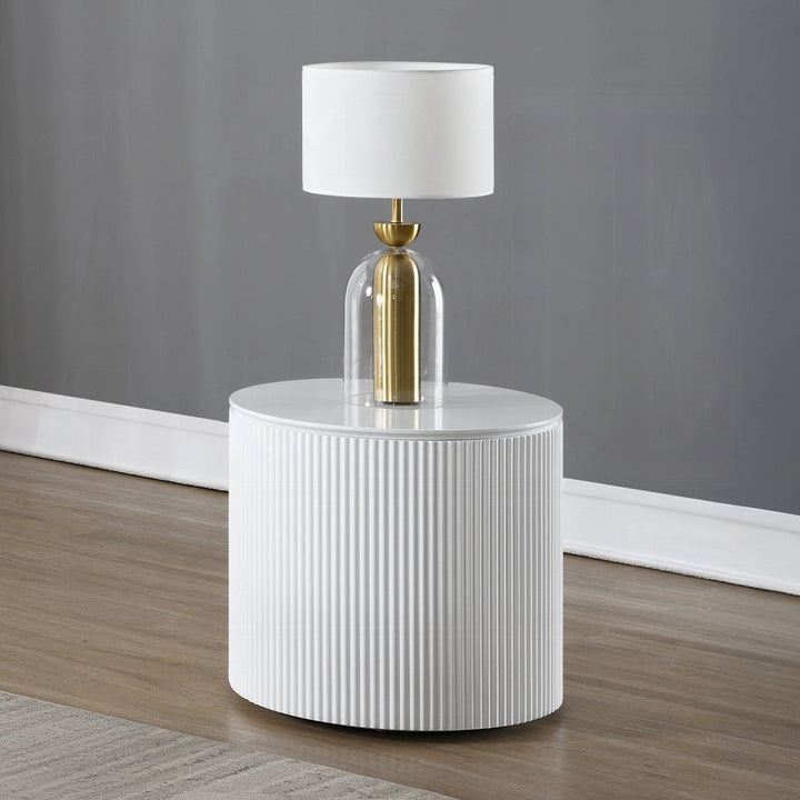 White side table with a gold and glass lamp against a gray wall.